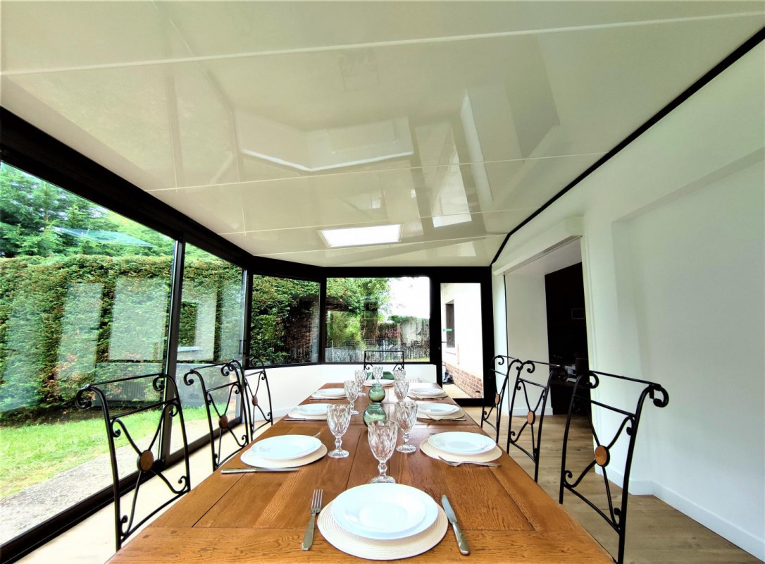 Big bright sunroom with a long oak dining table and garden views