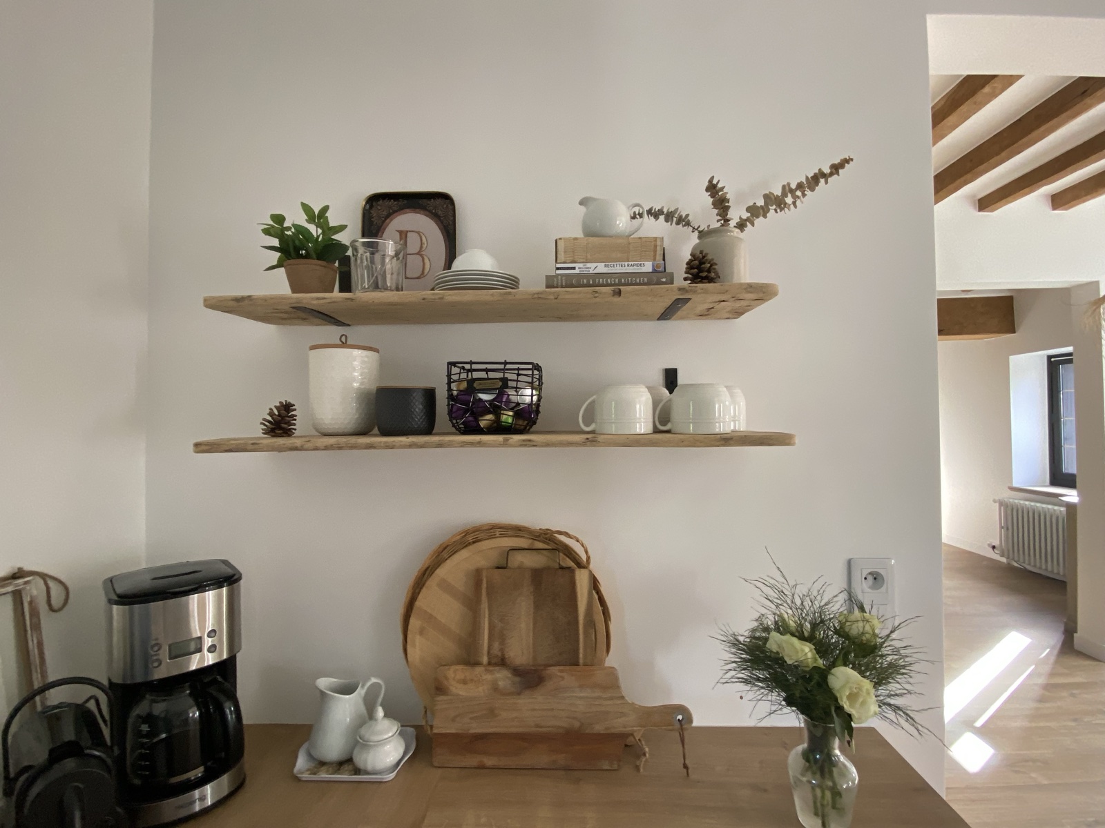 Open kitchen shelves with mugs, cookbooks and a small plant