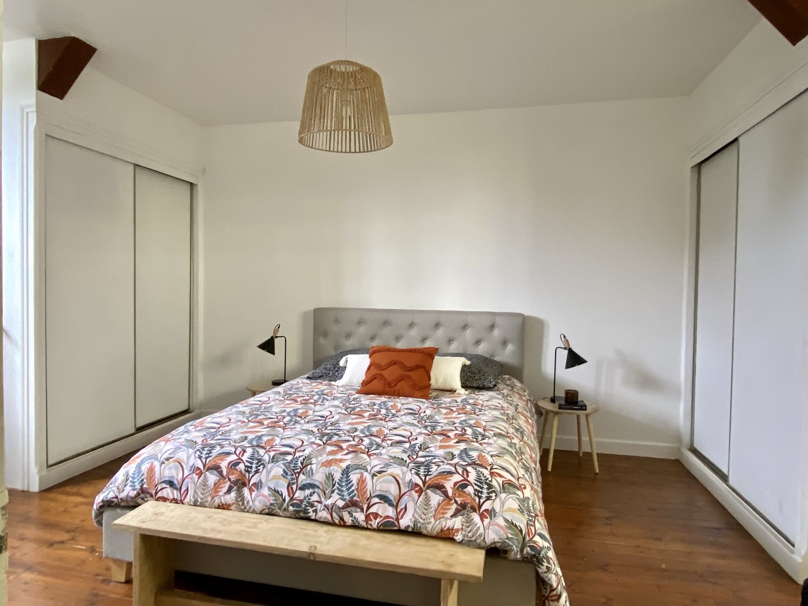 Upstairs double bedroom with patterned duvet, twin lamps and a woven pendant under the original beams