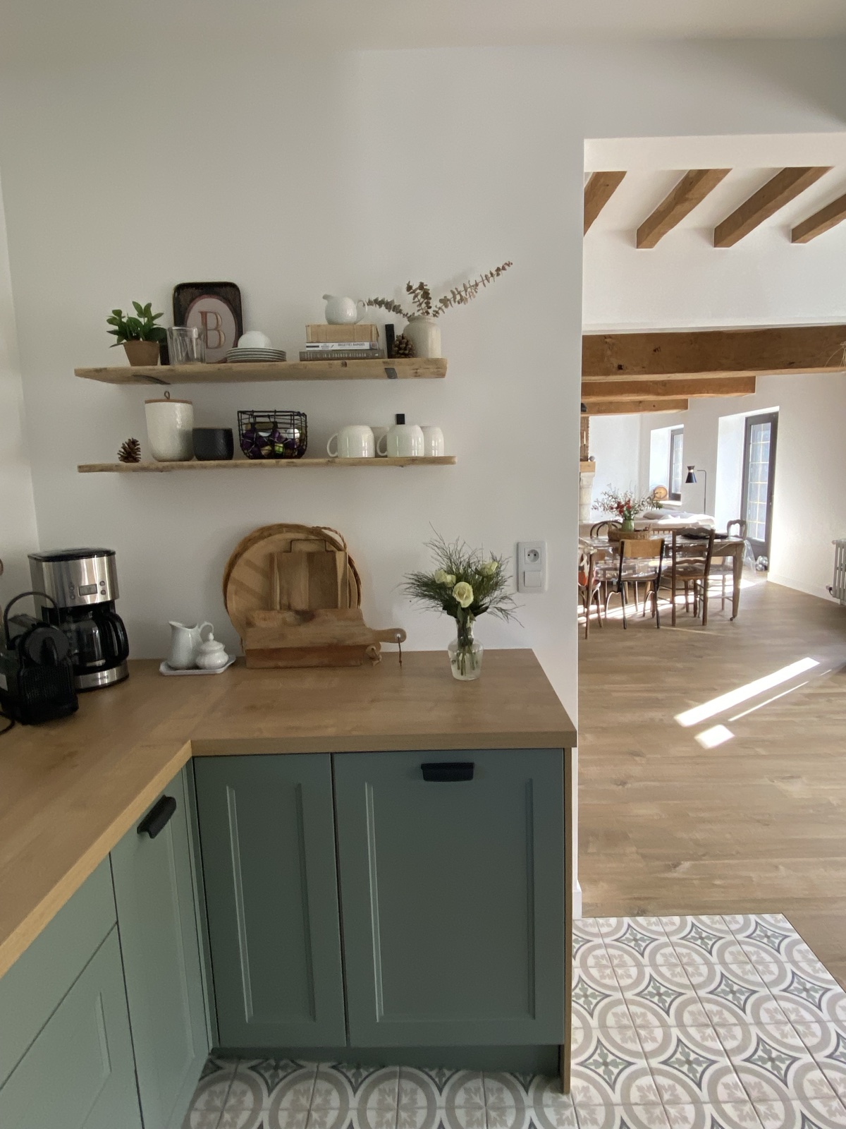 Kitchen open shelves with cookbooks, mugs and a fresh bouquet, dining table visible beyond